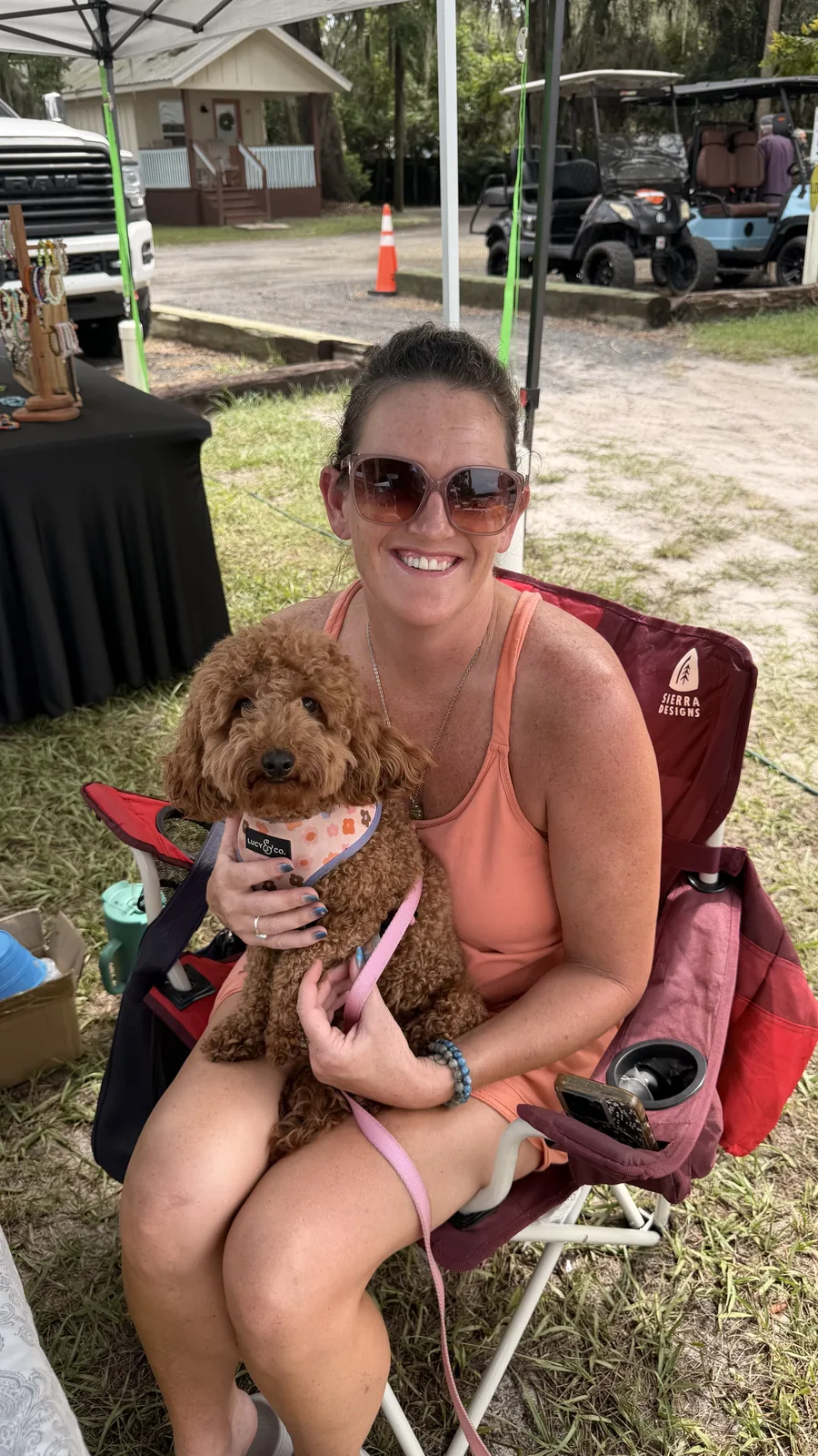 A guest and her dog relaxing among the golf carts at Cartoberfest
